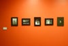 Black-framed photographs on a bright orange wall.