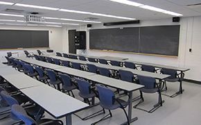 Tables with chairs facing chalkboards at the front of the room.