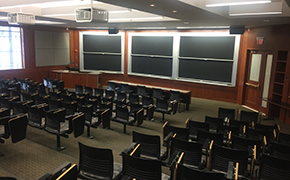 The front of a classroom, with rows of tiered seats facing a wall full of blackboards.