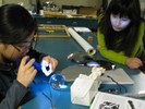 Photo of a student examining the glass ball with a flashlight and lens.