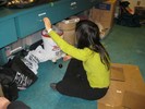 Photo of a student sitting on the floor and swinging a pendulum from her hand.