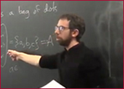 A men standing in front of a blackboard and pointing the blackboard with right hand.