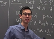 A men standing in front of a blackboard and facing front.