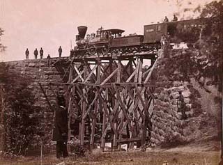 Photograph of locomotive on a railroad bridge, from 1865.