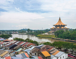 A photo of a grand building topped with gold in the background with a cluster of small shabby houses in the foreground.