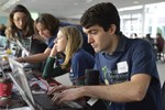 Several volunteers in matching tee shirts are sitting at computers.