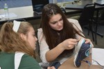 A woman is attaching electronic components to a tennis shoe.