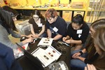 A group of girls sitting at a table, working on camera building.